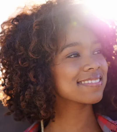 A relaxed young woman smiling while holding her skateboard